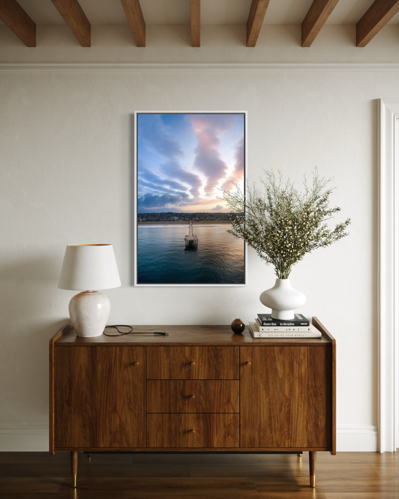 Wooden sideboard with a lamp, vase, and framed artwork on a wall.