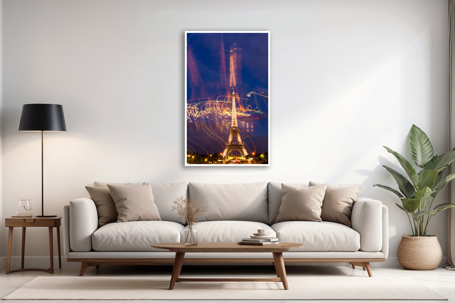 Modern living room with a white sofa, coffee table, and a framed photo of the Eiffel Tour. 