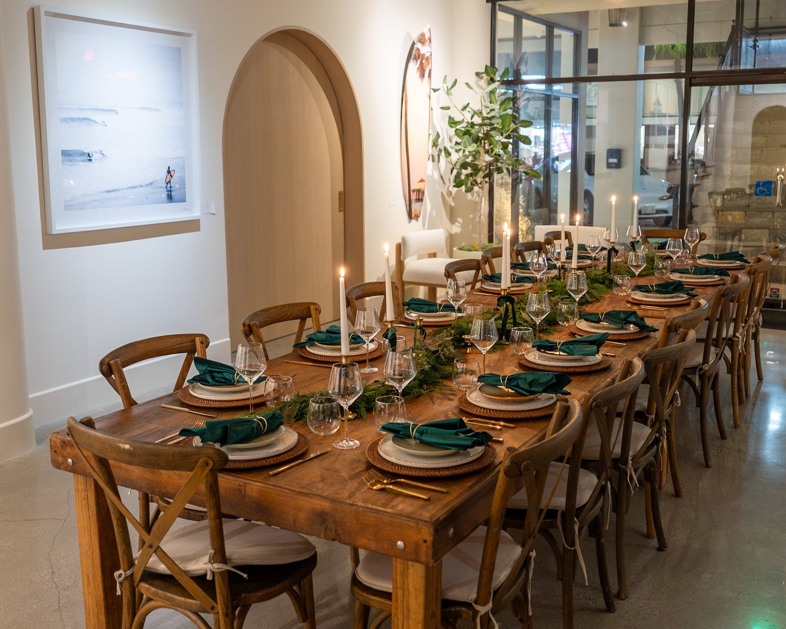 Long wooden dining table set for a meal with chairs in a modern interior setting.