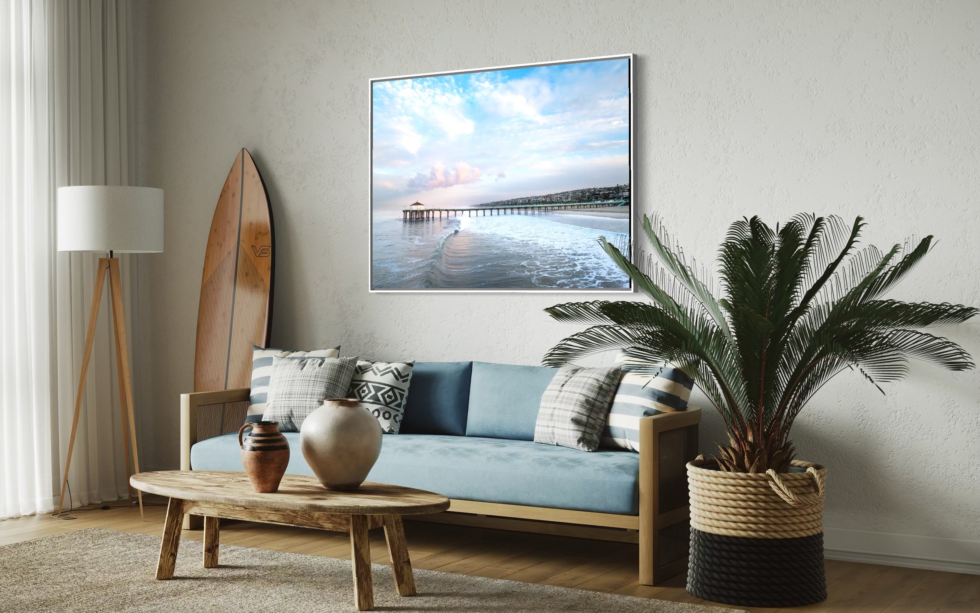 Modern living room with a piece of Bo Bridges fine art displaying a scenic image of the Manhattan Beach Pier, sofa, coffee table, and decorative items.