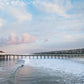 Manhattan Beach Pier extending into the ocean with a cloudy sky above.