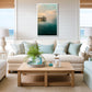 Living room with beige sofa, light blue cushions, wooden coffee table, and Manhattan Beach Pier artwork.